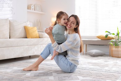 Photo of Happy mother with her cute little daughter on carpet at home