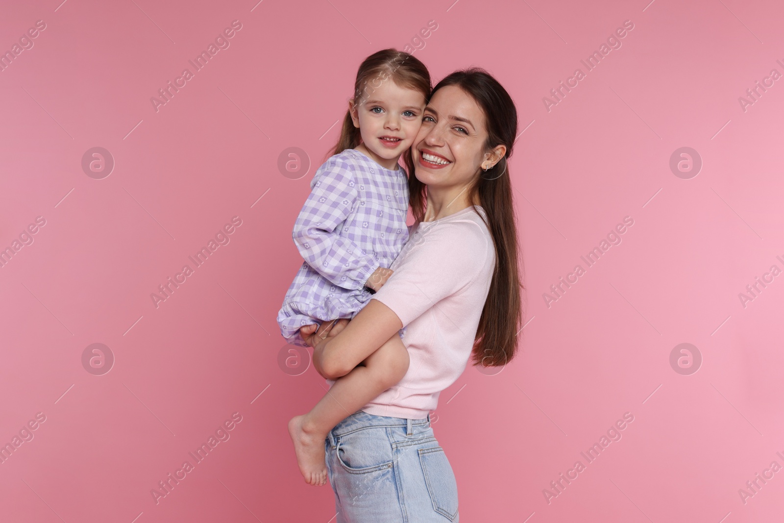 Photo of Portrait of happy mother with her cute little daughter on pink background