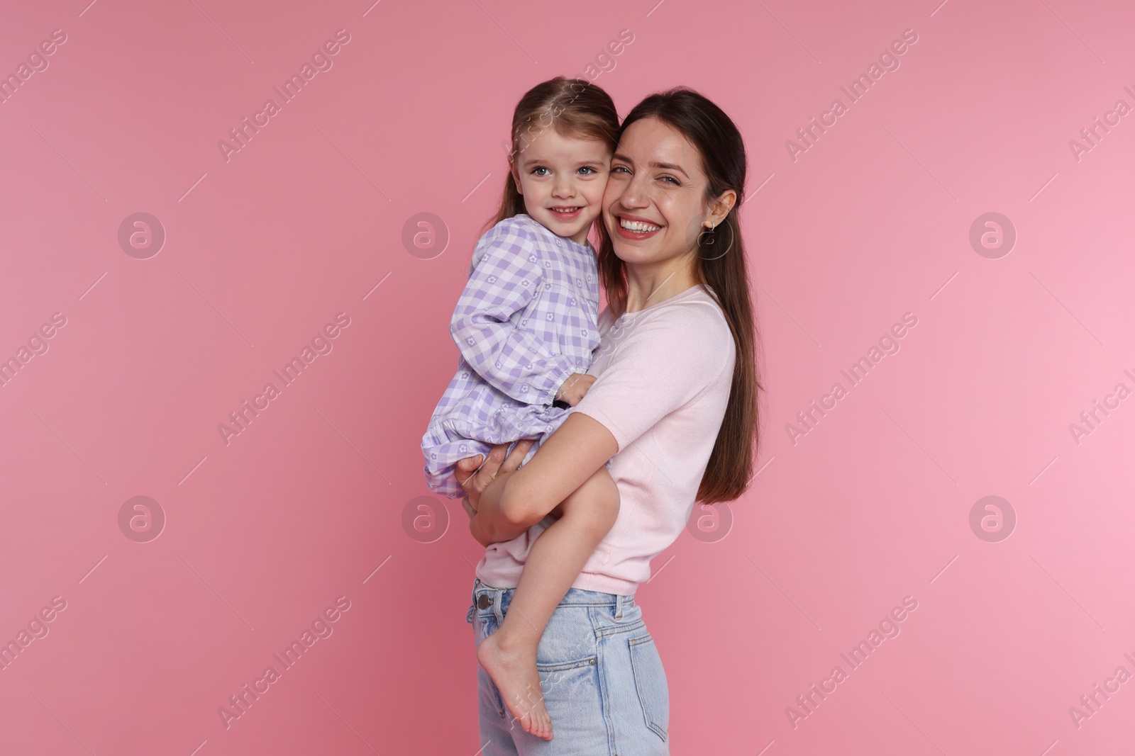 Photo of Portrait of happy mother with her cute little daughter on pink background