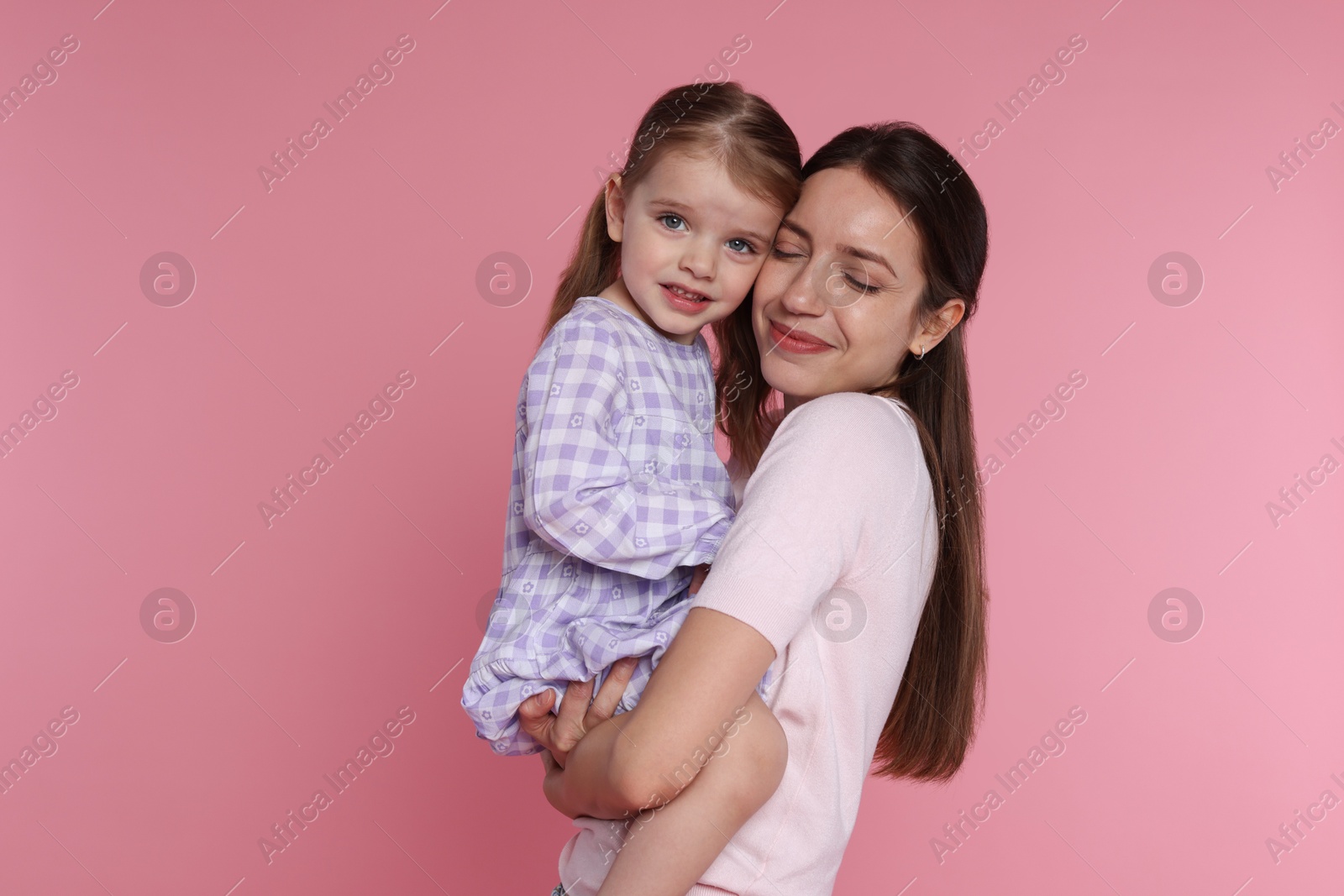 Photo of Portrait of beautiful mother with her cute little daughter on pink background