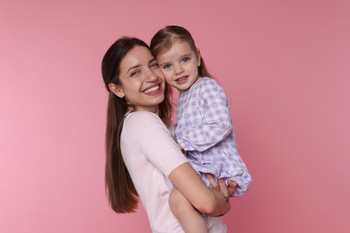 Photo of Portrait of happy mother with her cute little daughter on pink background