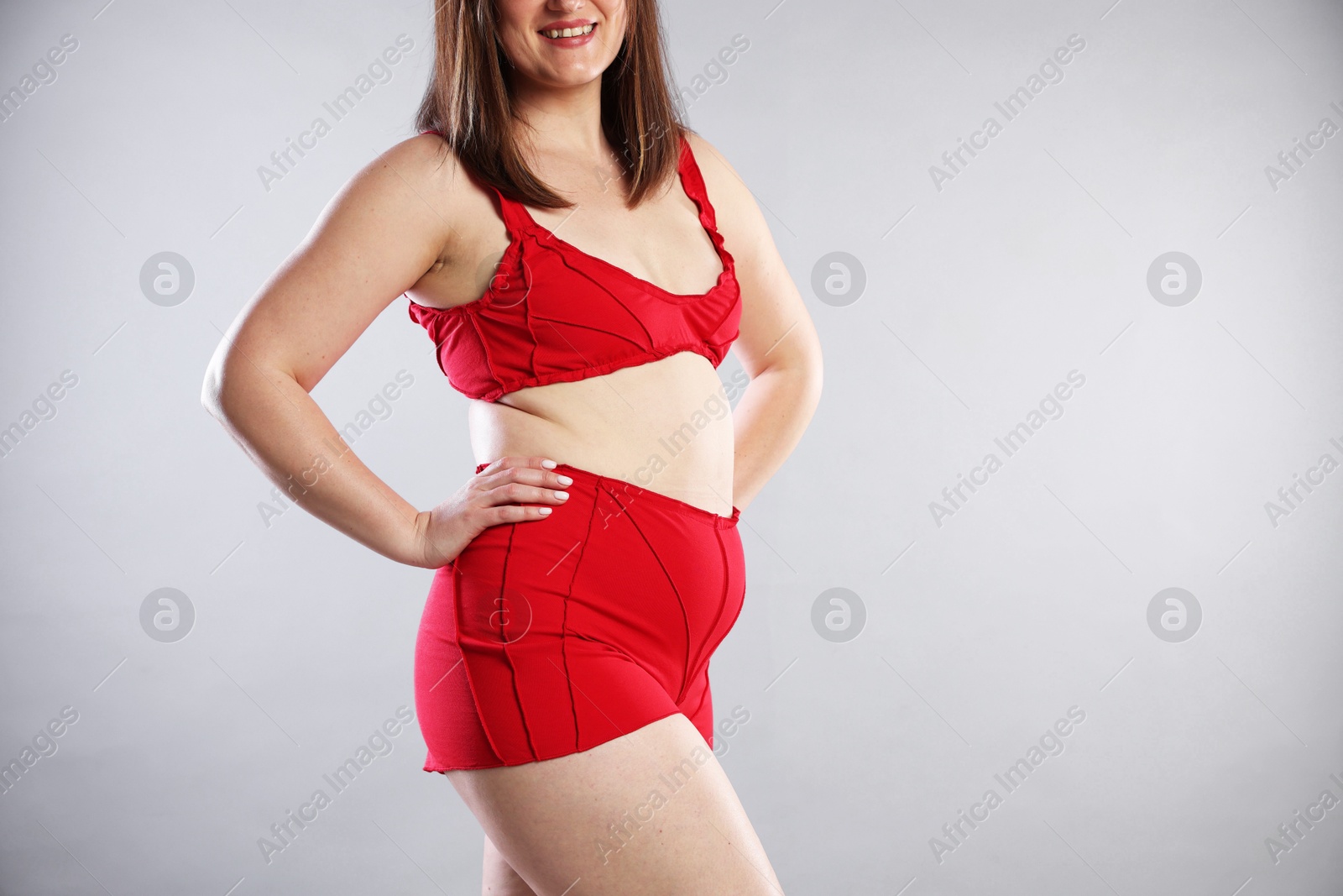 Photo of Cellulite problem. Woman in red underwear on light grey background, closeup. Space for text