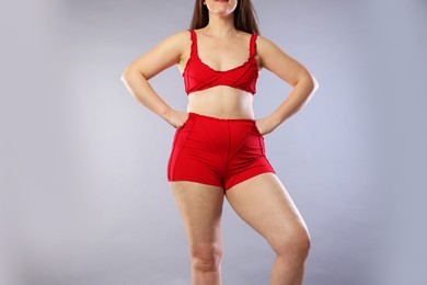 Photo of Woman in red underwear on light grey background, closeup. Cellulite problem