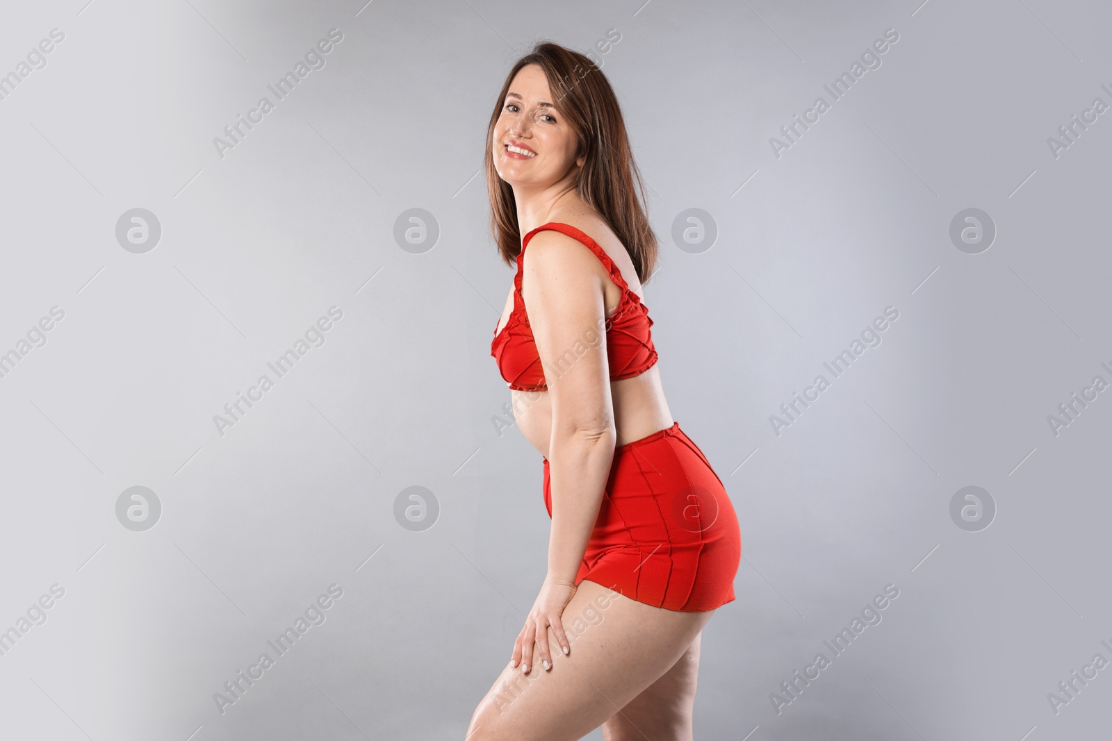 Photo of Woman in red underwear on light grey background. Cellulite problem