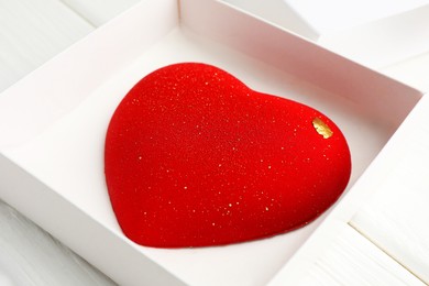 Photo of Heart shaped chocolate in box on white wooden table, closeup