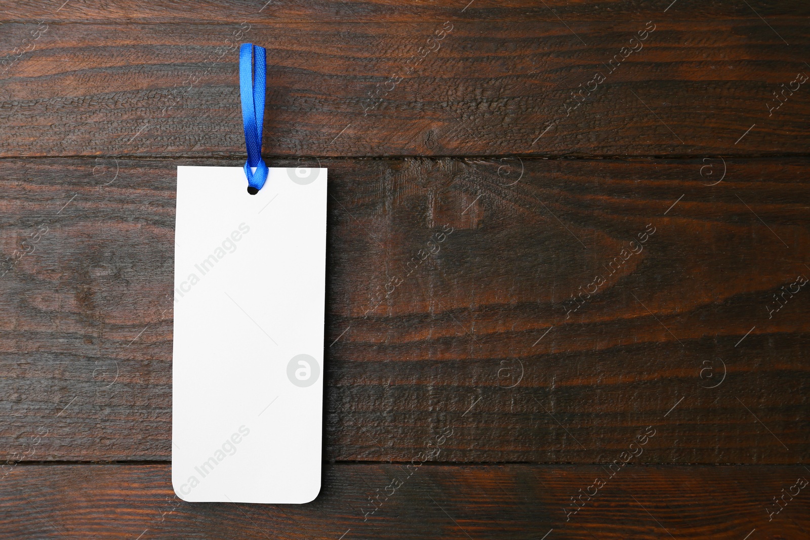 Photo of One paper bookmark on wooden background, top view. Space for text