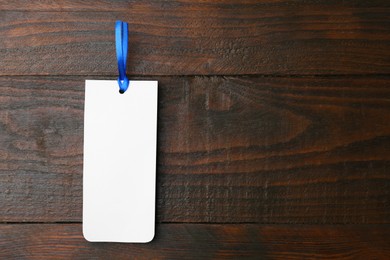 Photo of One paper bookmark on wooden background, top view. Space for text