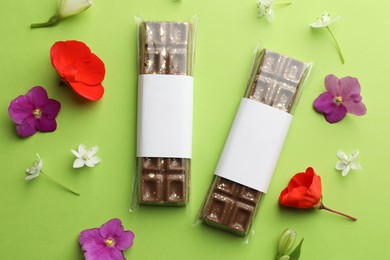 Photo of Delicious Dubai chocolate bars and flowers on green background, flat lay