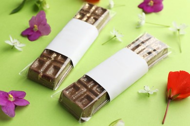 Delicious Dubai chocolate bars and flowers on green background, closeup