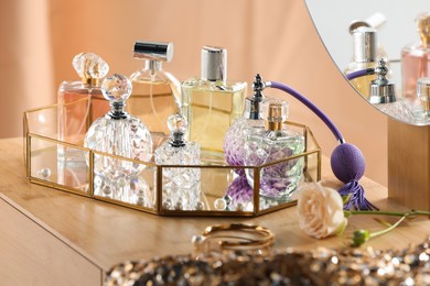 Photo of Different luxury perfumes on wooden dressing table indoors