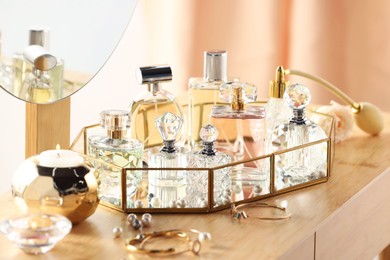 Photo of Different luxury perfumes on wooden dressing table indoors