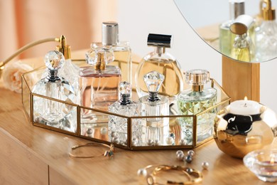 Photo of Different luxury perfumes on wooden dressing table indoors