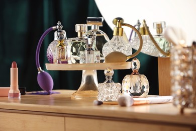 Photo of Different luxury perfumes on wooden dressing table indoors