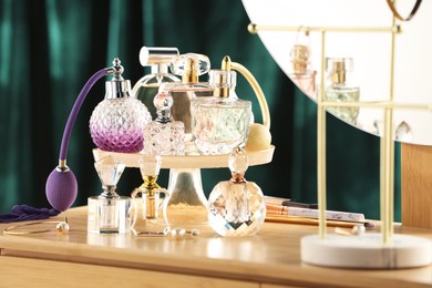 Photo of Different luxury perfumes on wooden dressing table indoors