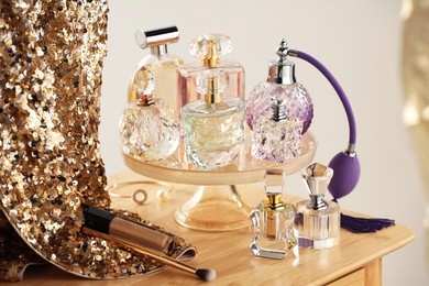 Photo of Different luxury perfumes on wooden dressing table indoors
