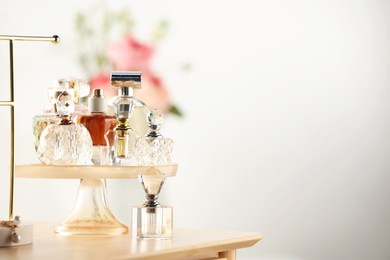 Photo of Different luxury perfumes on wooden dressing table indoors, space for text