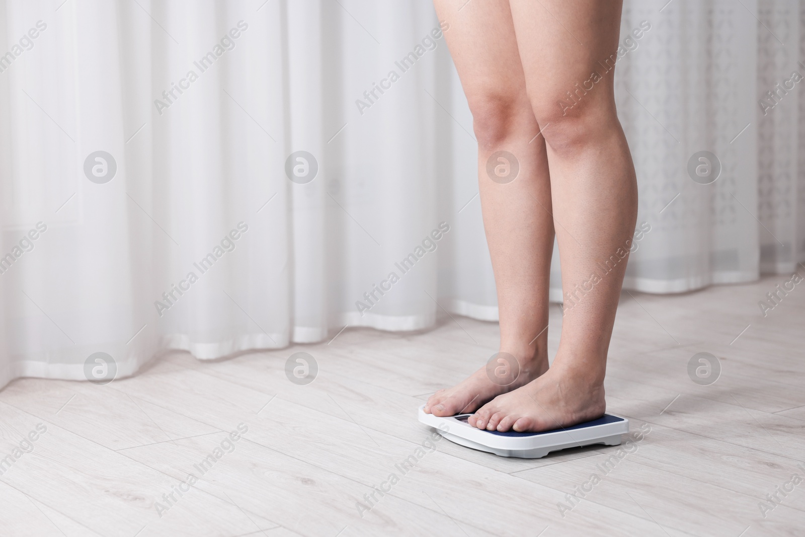 Photo of Woman on scales indoors, closeup with space for text. Weight loss