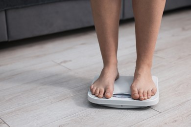 Photo of Woman on scales indoors, closeup with space for text. Weight loss