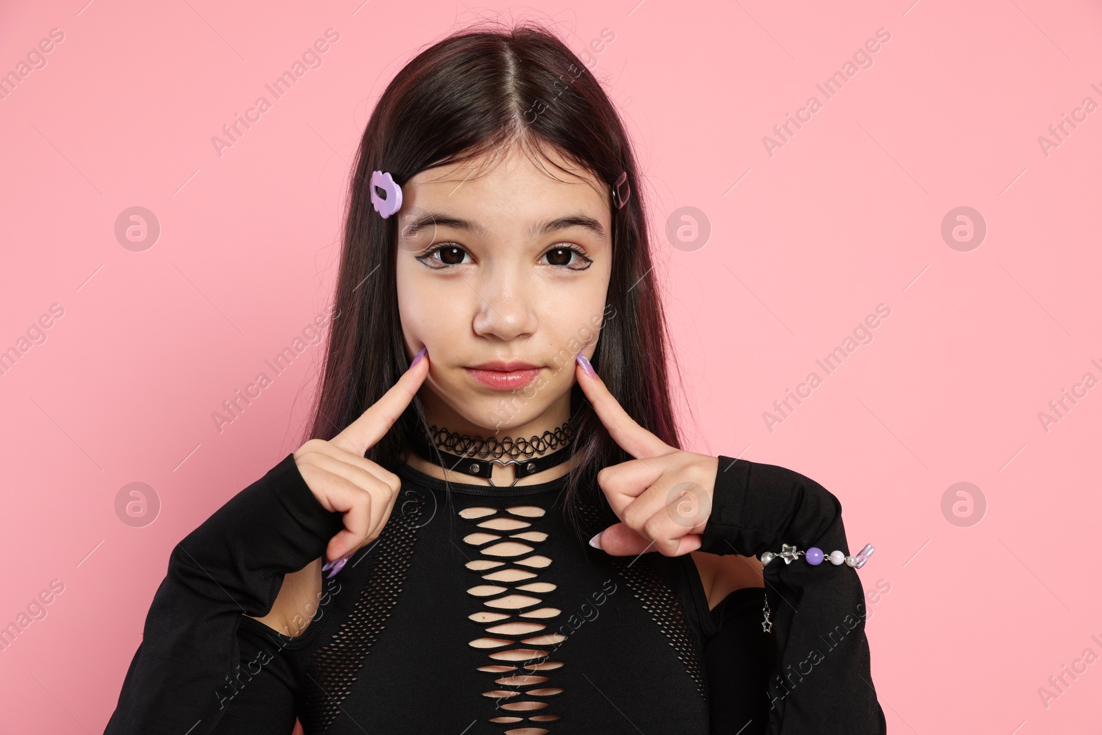 Photo of Teenage girl posing on pink background. Makeup and clothes in anime style