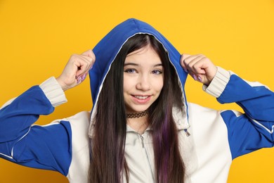 Photo of Teenage girl in stylish clothes posing on orange background. Makeup in anime style