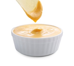 Photo of Dipping potato chip into tasty cheese sauce on white background, closeup