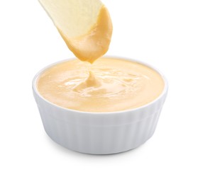 Photo of Dipping potato chip into tasty cheese sauce on white background, closeup