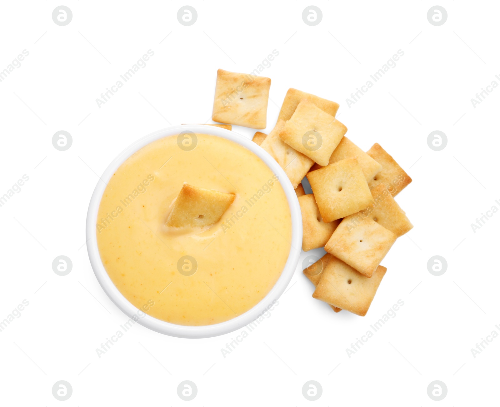 Photo of Tasty cheese dipping sauce in bowl and crackers isolated on white, top view