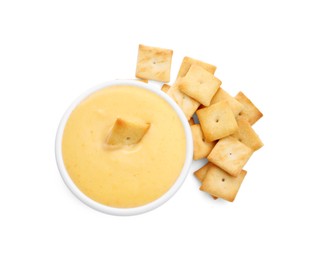 Photo of Tasty cheese dipping sauce in bowl and crackers isolated on white, top view