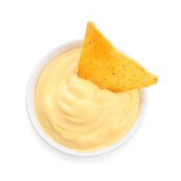 Photo of Tasty cheese dipping sauce in bowl and nacho chip isolated on white, top view