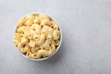 Photo of Delicious pasta with cheese sauce in bowl on grey table, top view. Space for text