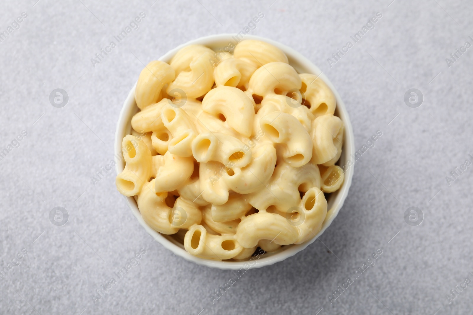 Photo of Delicious pasta with cheese sauce in bowl on grey table, top view