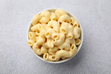 Photo of Delicious pasta with cheese sauce in bowl on grey table, top view