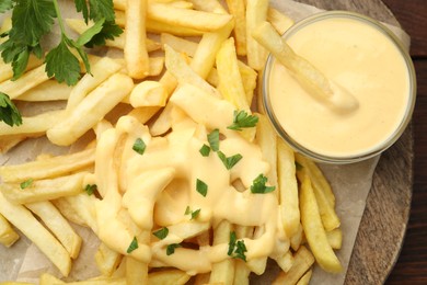 Photo of Delicious cheese sauce in bowl, French fries and parsley on table, top view