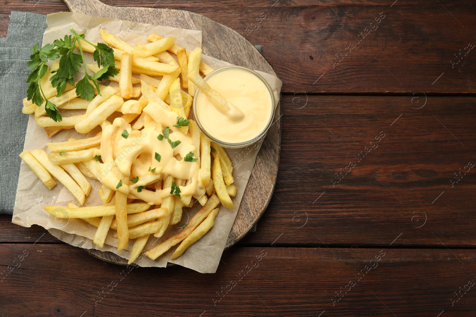 Delicious cheese sauce in bowl, French fries and parsley on wooden table, top view. Space for text Photo of Delicious cheese sauce in bowl, French fries and parsley on wooden table, top view. Space for text