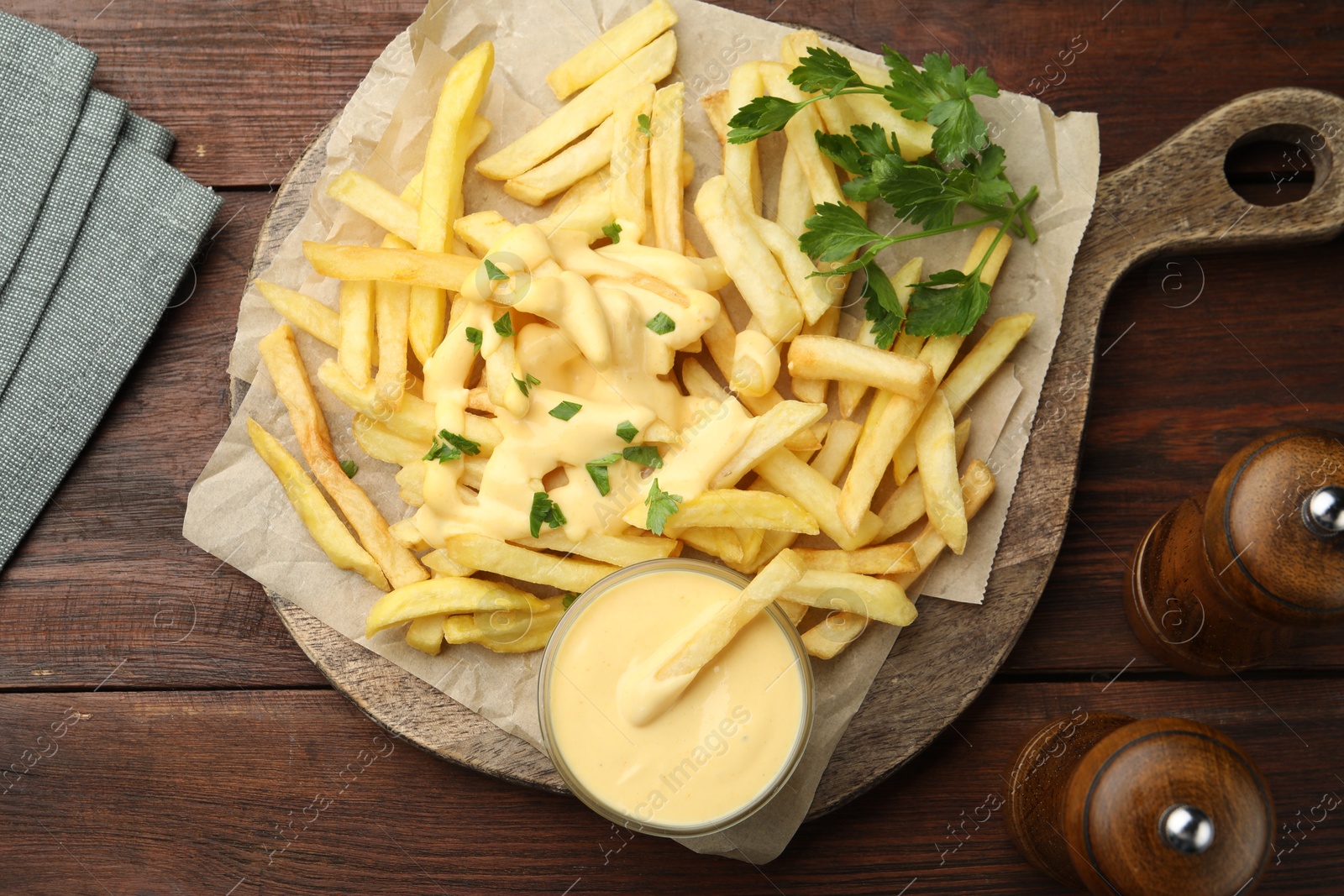 Delicious cheese sauce in bowl, French fries and parsley on wooden table, flat lay Photo of Delicious cheese sauce in bowl, French fries and parsley on wooden table, flat lay