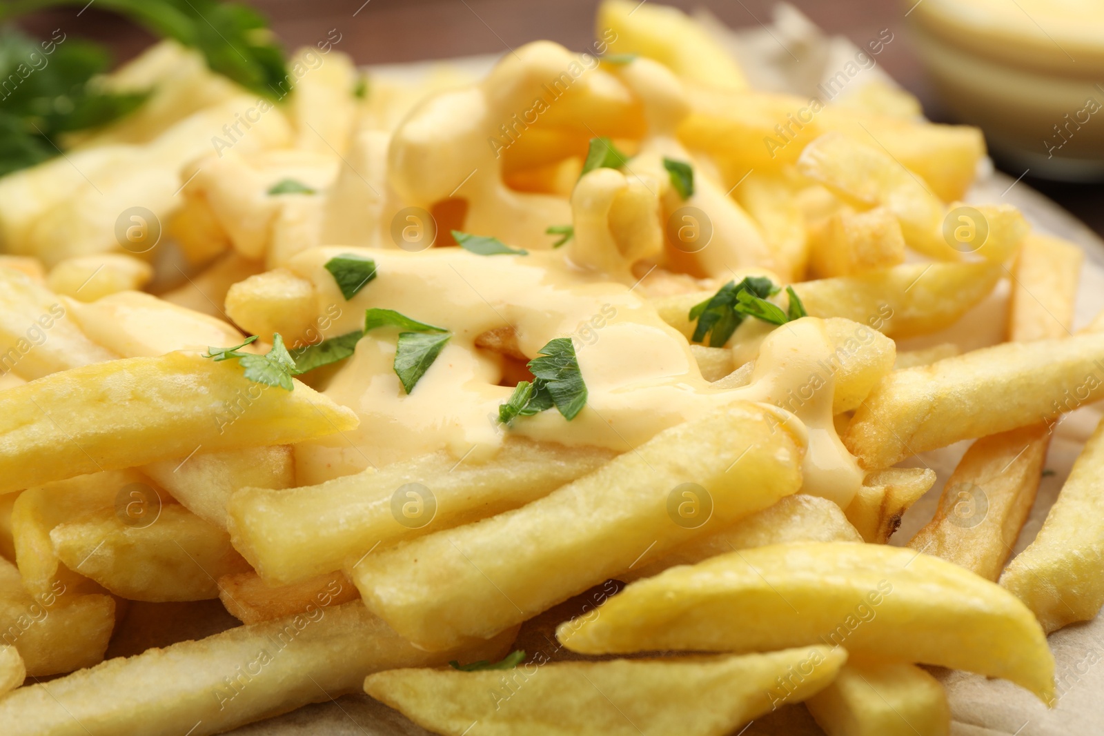 French fries with cheese sauce and parsley on table, closeup Photo of French fries with cheese sauce and parsley on table, closeup