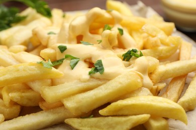 French fries with cheese sauce and parsley on table, closeup