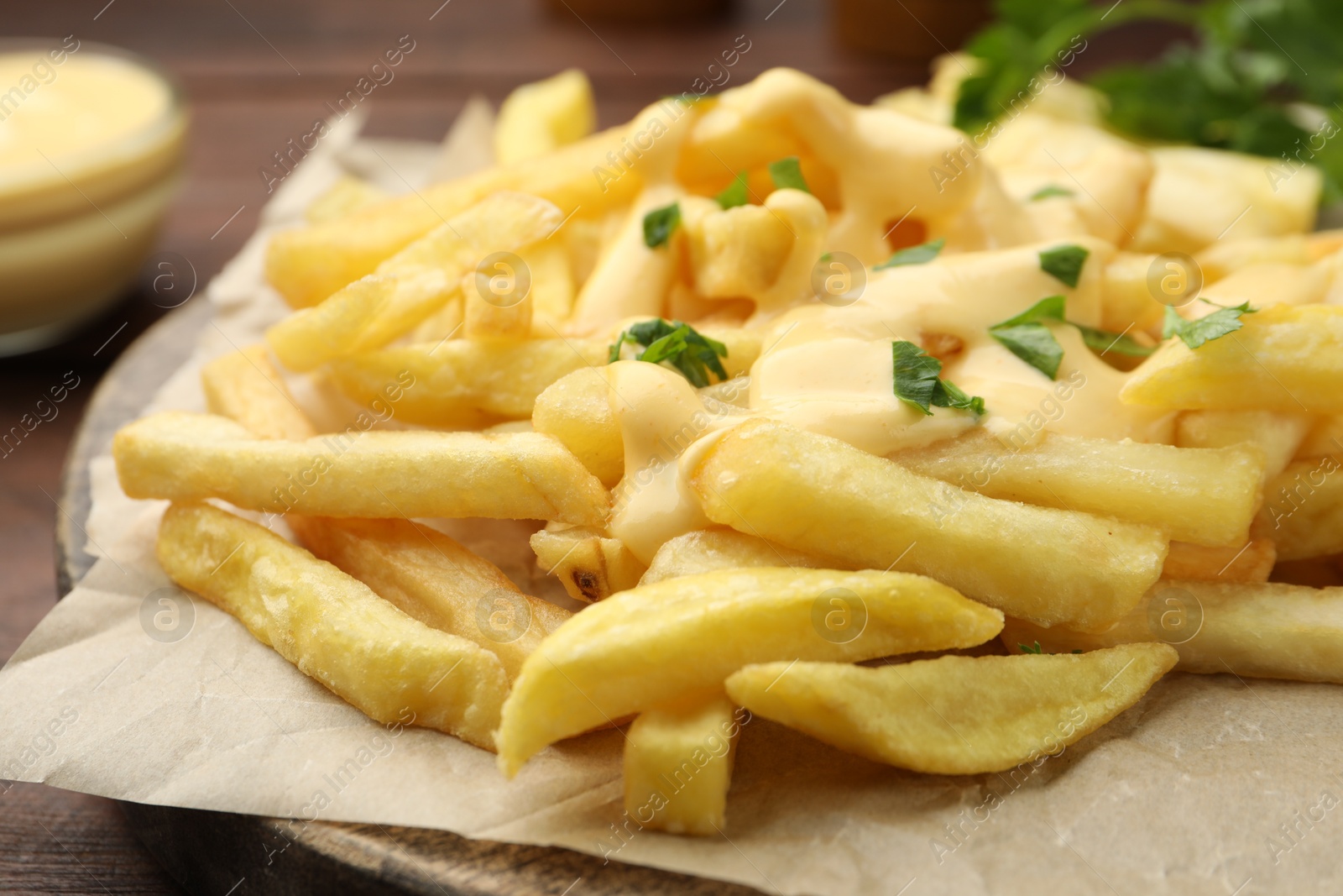 French fries with cheese sauce and parsley on table, closeup Photo of French fries with cheese sauce and parsley on table, closeup