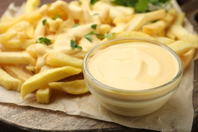 Photo of Delicious cheese sauce in bowl, French fries and parsley on table, closeup