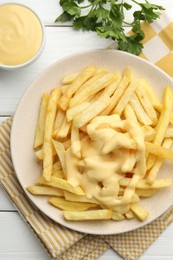 Photo of French fries with cheese sauce and parsley on white wooden table, flat lay