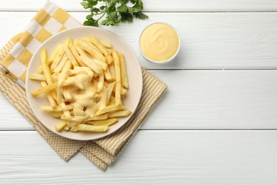 Photo of French fries with cheese sauce and parsley on white wooden table, flat lay. Space for text