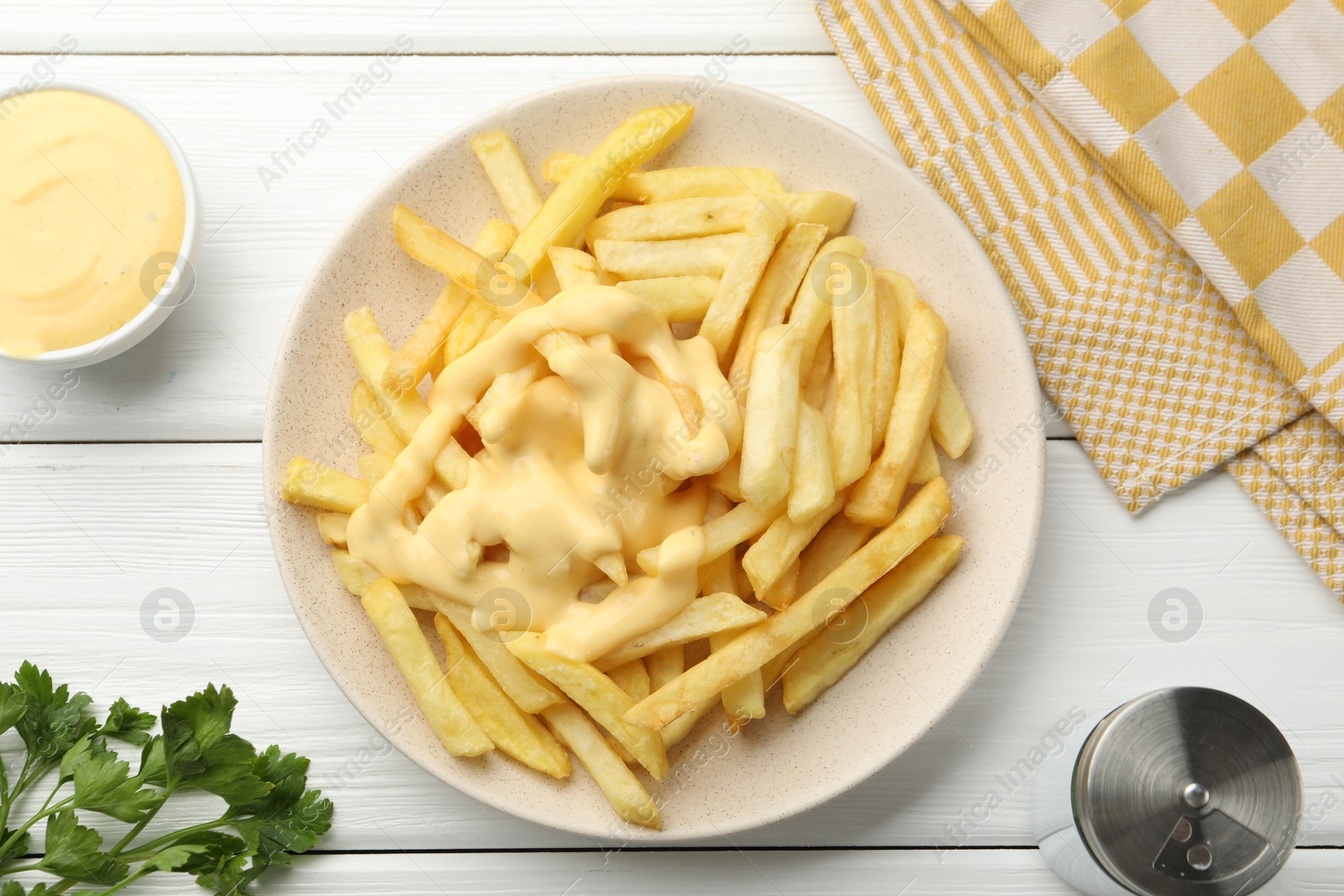 French fries with cheese sauce and parsley on white wooden table, flat lay Photo of French fries with cheese sauce and parsley on white wooden table, flat lay