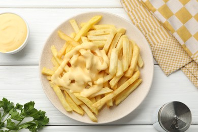 Photo of French fries with cheese sauce and parsley on white wooden table, flat lay