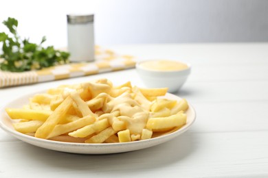 Photo of French fries with cheese sauce on white wooden table, closeup. Space for text