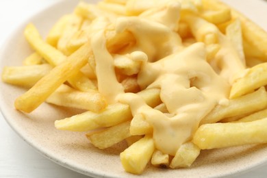 Photo of French fries with cheese sauce on table, closeup