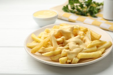 Photo of French fries with cheese sauce and parsley on white wooden table, closeup