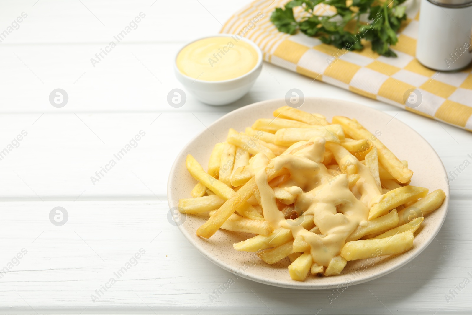 French fries with cheese sauce and parsley on white wooden table, closeup. Space for text Photo of French fries with cheese sauce and parsley on white wooden table, closeup. Space for text