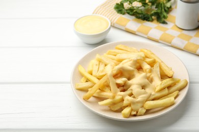 Photo of French fries with cheese sauce and parsley on white wooden table, closeup. Space for text
