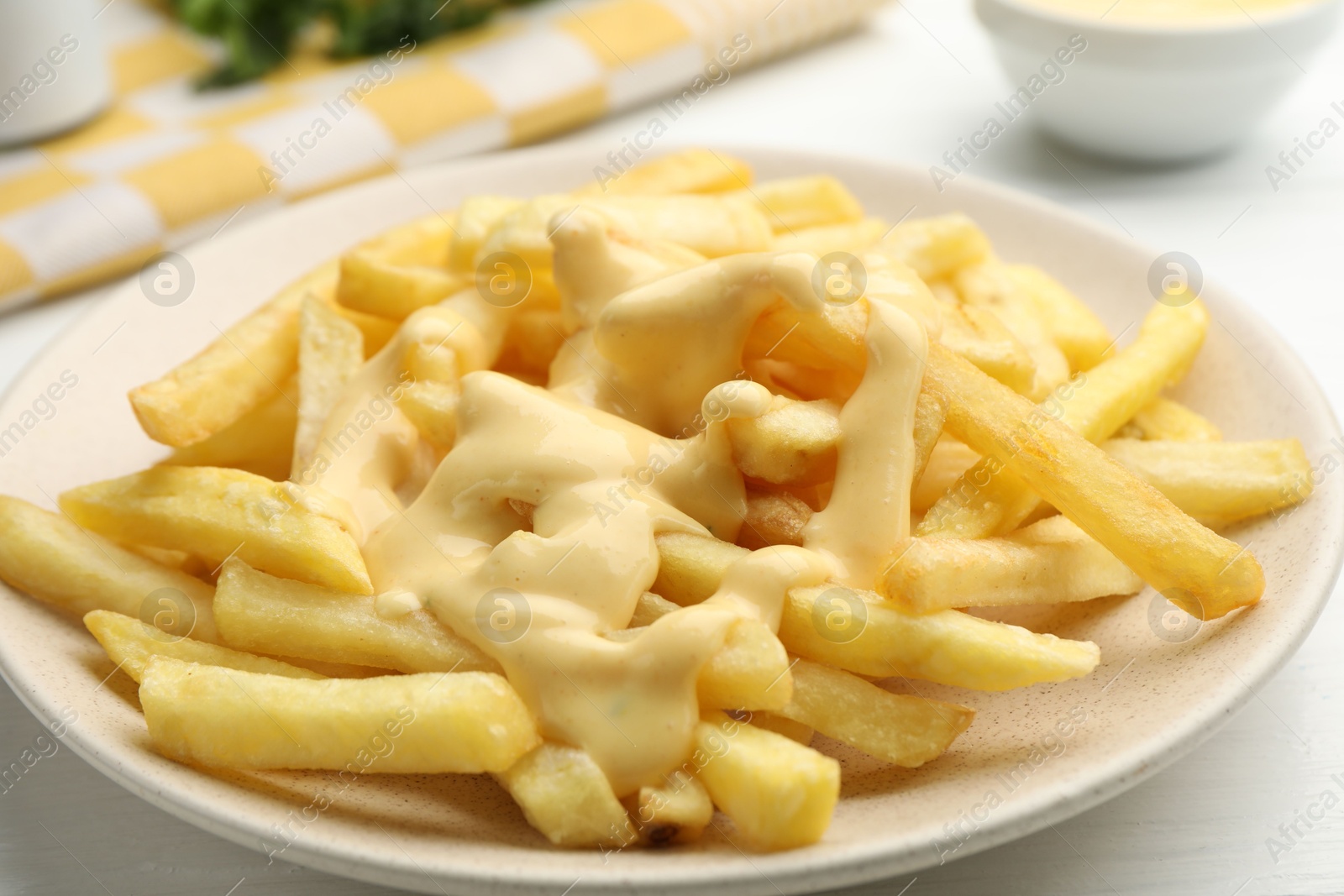French fries with cheese sauce on white table, closeup Photo of French fries with cheese sauce on white table, closeup