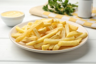 Photo of French fries with cheese sauce and parsley on white wooden table, closeup